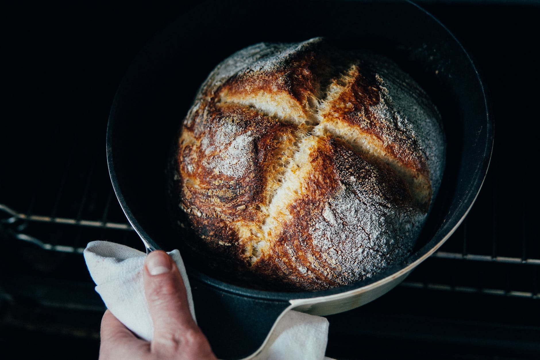 person pulling out freshly baked bread from oven